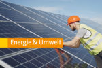 Energie & Umwelt. Person mit Helm und Warnweste untersucht Solaranlage.