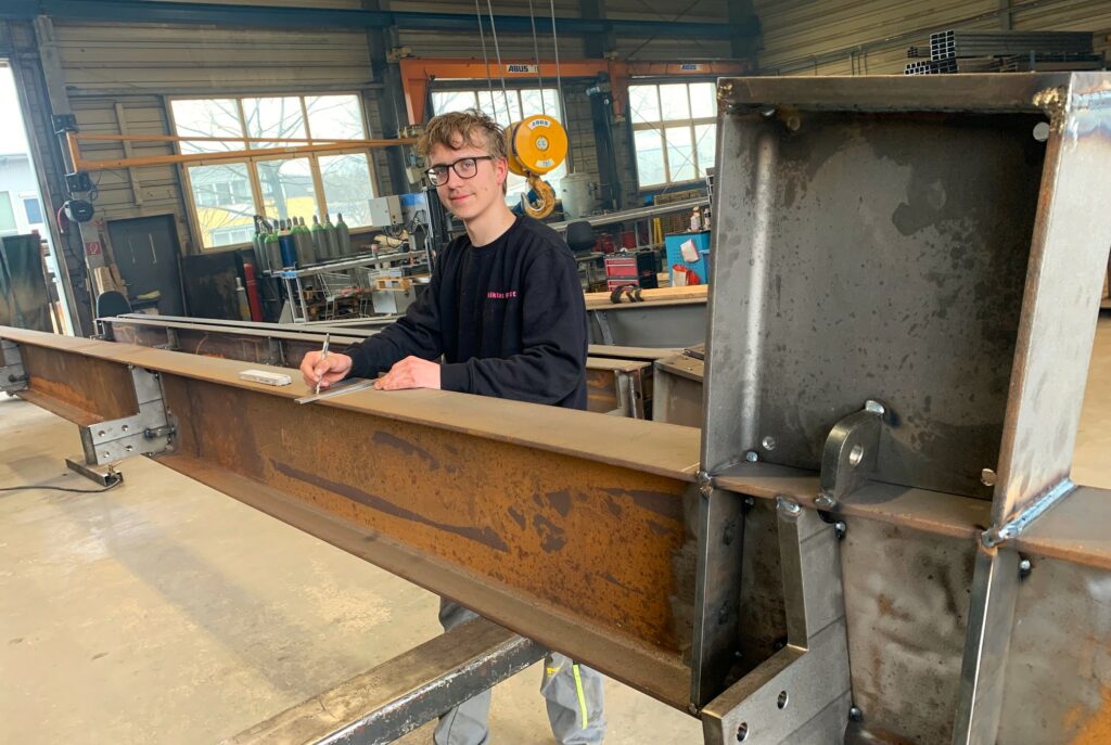 Ein junge Mann arbeitet als Metallbauer in der Werkstatt.