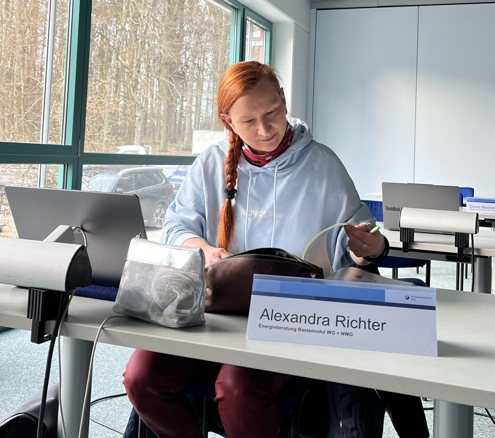Kursteilnehmerin sitzt im Lehrsaal an ihren Unterlagen und am Laptop
