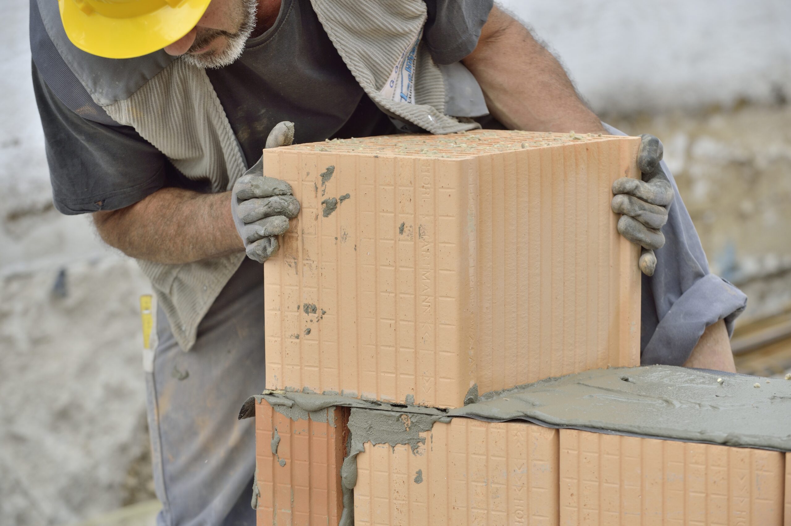 Ein Maurer verputzt Ziegel auf einer Baustelle.