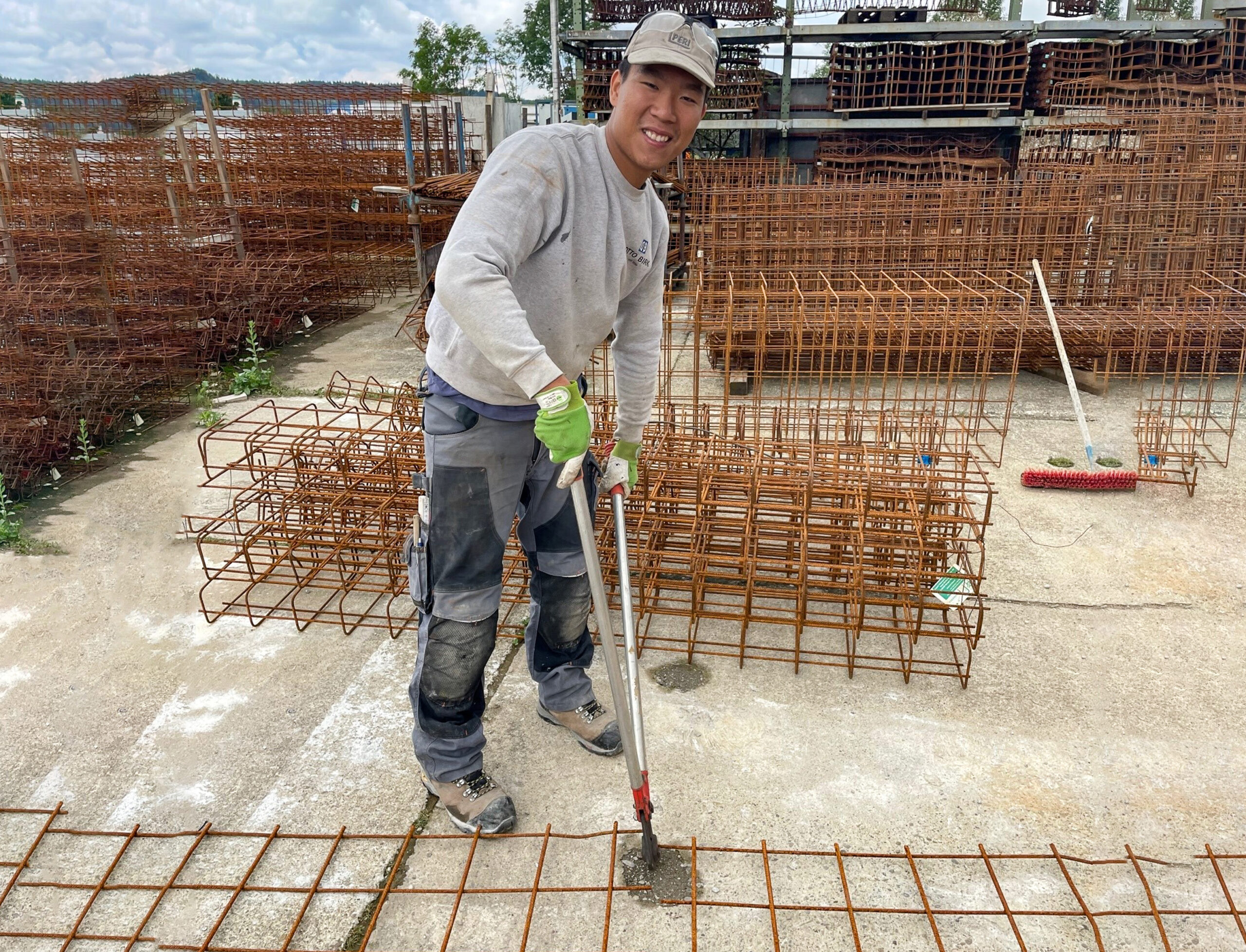 Ein junger Mann arbeitet auf der Baustelle und schneidet Stahlmatten zu.